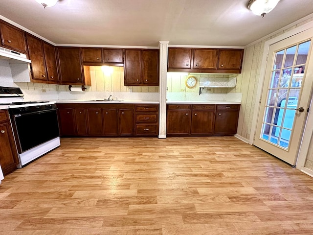 kitchen with dark brown cabinetry, sink, white range oven, backsplash, and light hardwood / wood-style floors