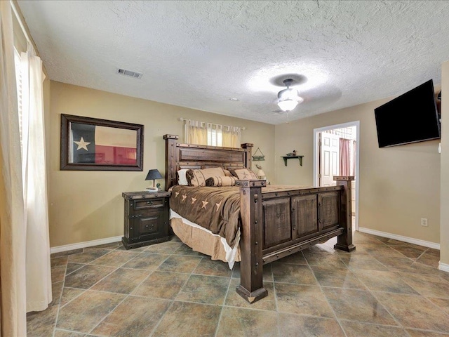 21441 Fm 705, Broaddus, TX 75929 - bedroom with baseboards, multiple windows, dark stone finish floors, and a textured ceiling