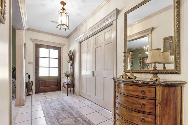 tiled entryway with an inviting chandelier and ornamental molding