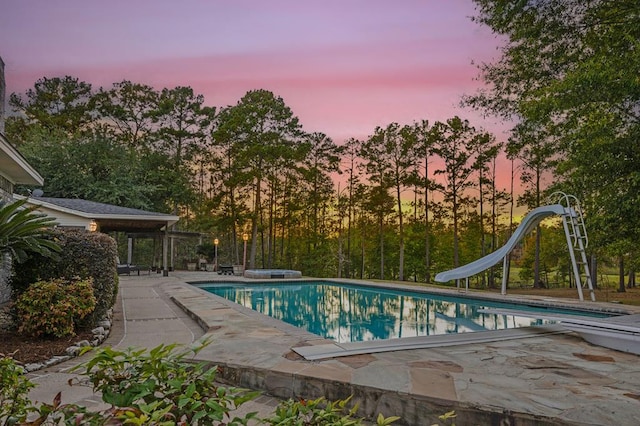 pool at dusk featuring a water slide