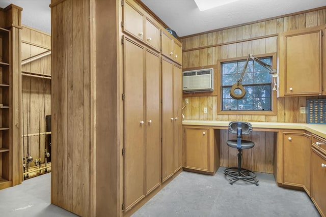 kitchen with a wall mounted air conditioner, built in desk, and wooden walls