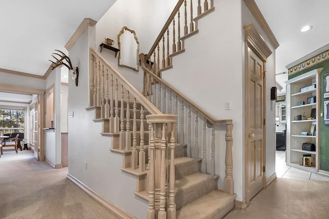 stairway with carpet floors and ornamental molding