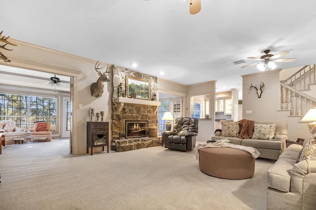 carpeted living room with a fireplace, plenty of natural light, crown molding, and ceiling fan