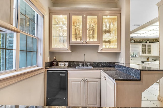 bar featuring sink, light tile patterned floors, and dark stone counters