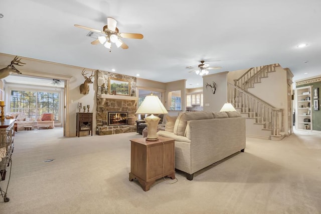 living room with ceiling fan, a stone fireplace, and light carpet