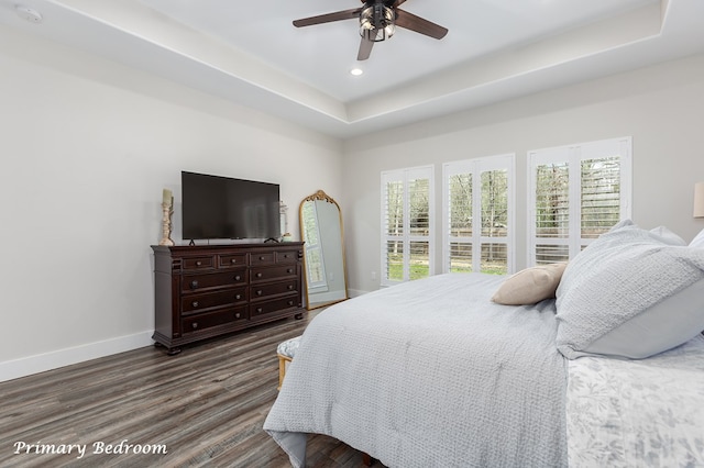 bedroom featuring baseboards, recessed lighting, ceiling fan, dark wood-type flooring, and a raised ceiling