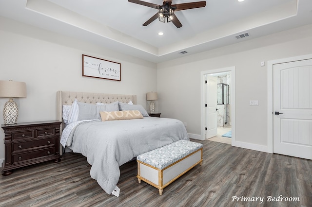 bedroom with a tray ceiling, visible vents, and wood finished floors