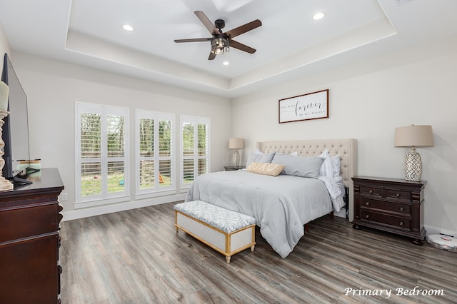 bedroom with recessed lighting, a raised ceiling, and wood finished floors