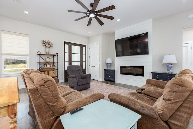 living area with a ceiling fan, wood finished floors, recessed lighting, a large fireplace, and baseboards