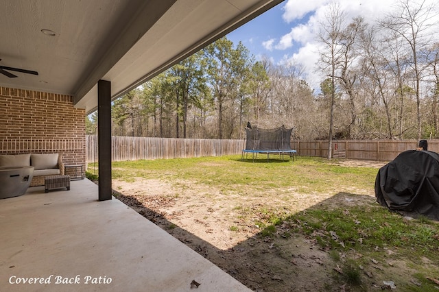 view of yard featuring a patio area, a fenced backyard, a ceiling fan, and a trampoline