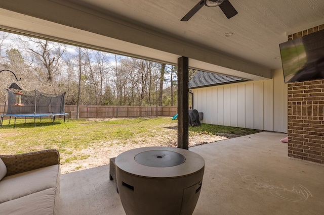 view of patio featuring a trampoline, ceiling fan, and fence