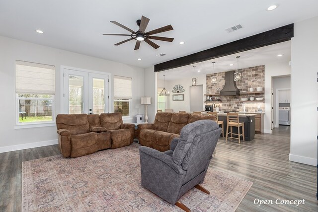 living area with beamed ceiling, baseboards, and wood finished floors