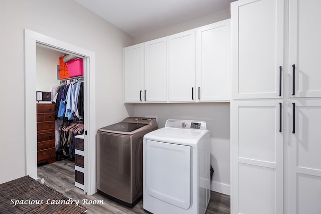 washroom featuring separate washer and dryer, wood finished floors, and cabinet space