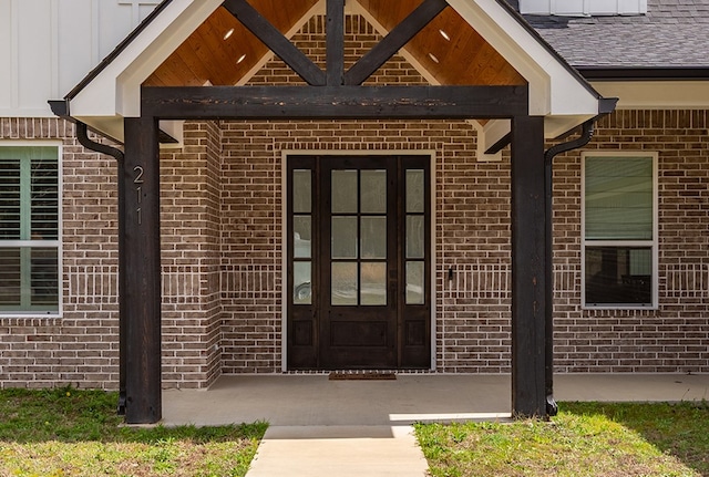 view of exterior entry featuring brick siding and board and batten siding