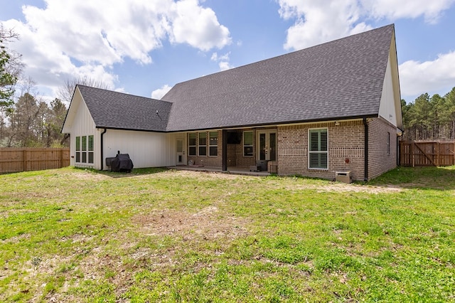 back of property featuring french doors, brick siding, a yard, and fence