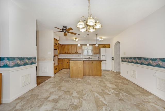 kitchen with a center island, ceiling fan with notable chandelier, hanging light fixtures, decorative backsplash, and white fridge with ice dispenser