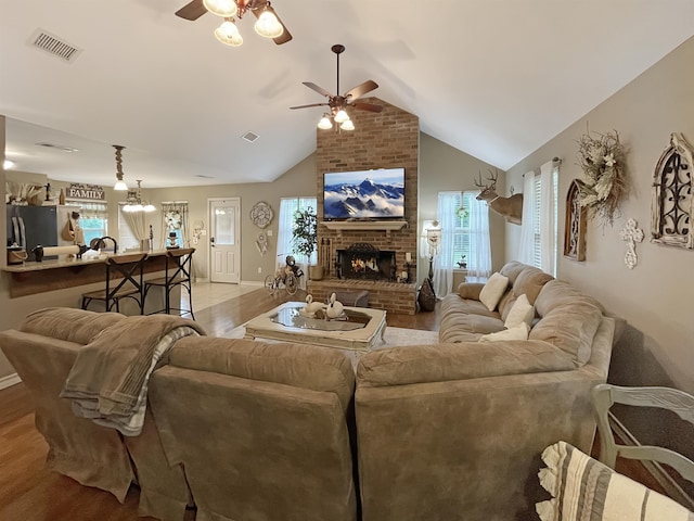 living room featuring light hardwood / wood-style floors, a brick fireplace, ceiling fan, and lofted ceiling