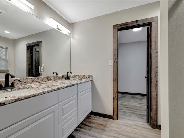 242 W Magnolia, Huntington, TX 75949 - full bathroom featuring double vanity, wood finished floors, baseboards, and a sink