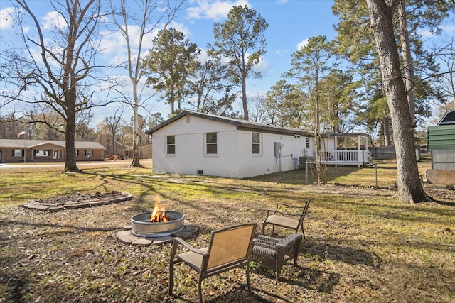 back of property with an outdoor fire pit and a yard