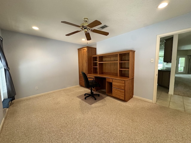 unfurnished office featuring light carpet, a textured ceiling, and ceiling fan