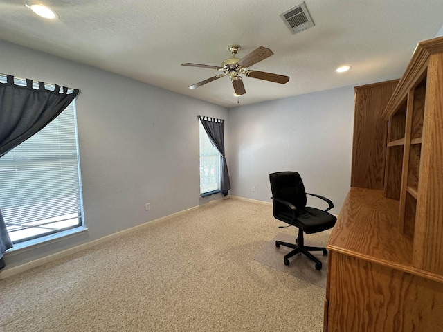 unfurnished office with light carpet, ceiling fan, and a textured ceiling