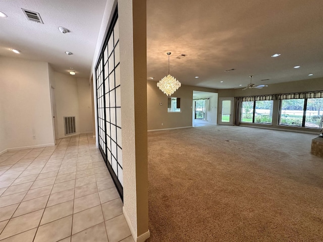 carpeted spare room featuring ceiling fan with notable chandelier and a textured ceiling