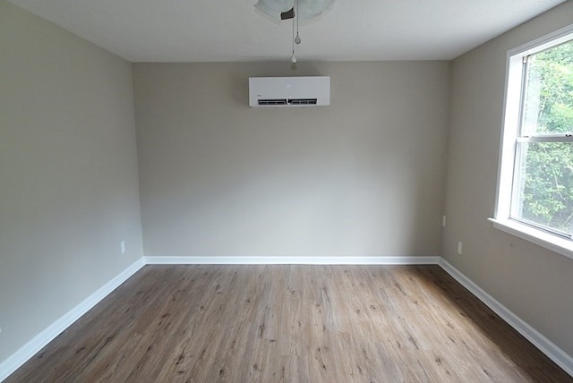 unfurnished dining area with light hardwood / wood-style floors, a wall unit AC, and a healthy amount of sunlight