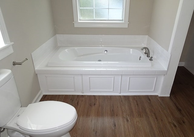 bathroom featuring hardwood / wood-style flooring, a bath, and toilet