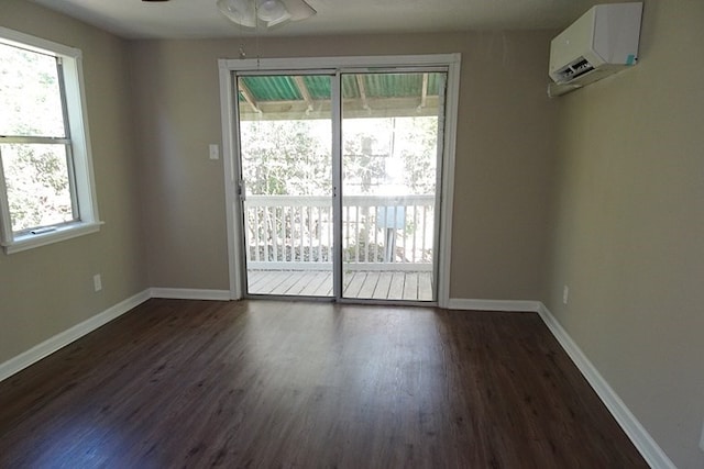 spare room with an AC wall unit, ceiling fan, dark wood-type flooring, and a healthy amount of sunlight