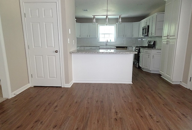 kitchen with white cabinets, dark hardwood / wood-style floors, stainless steel appliances, and tasteful backsplash