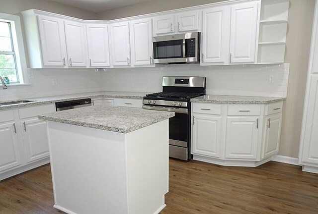 kitchen with white cabinets, a kitchen island, stainless steel appliances, and dark wood-type flooring