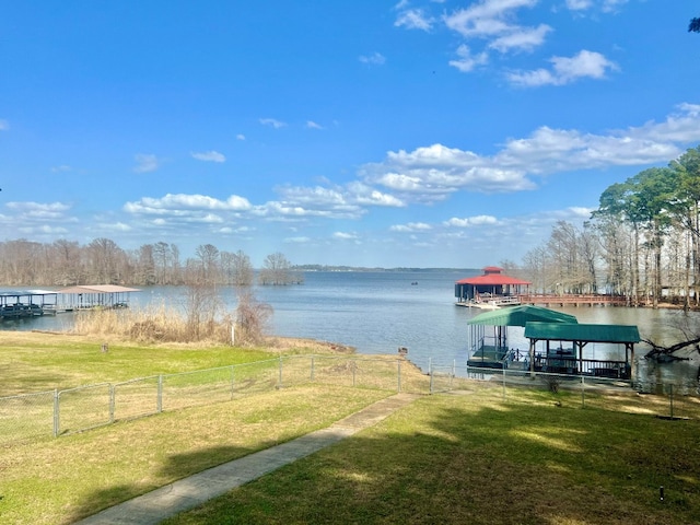 dock area with a lawn, a water view, and fence