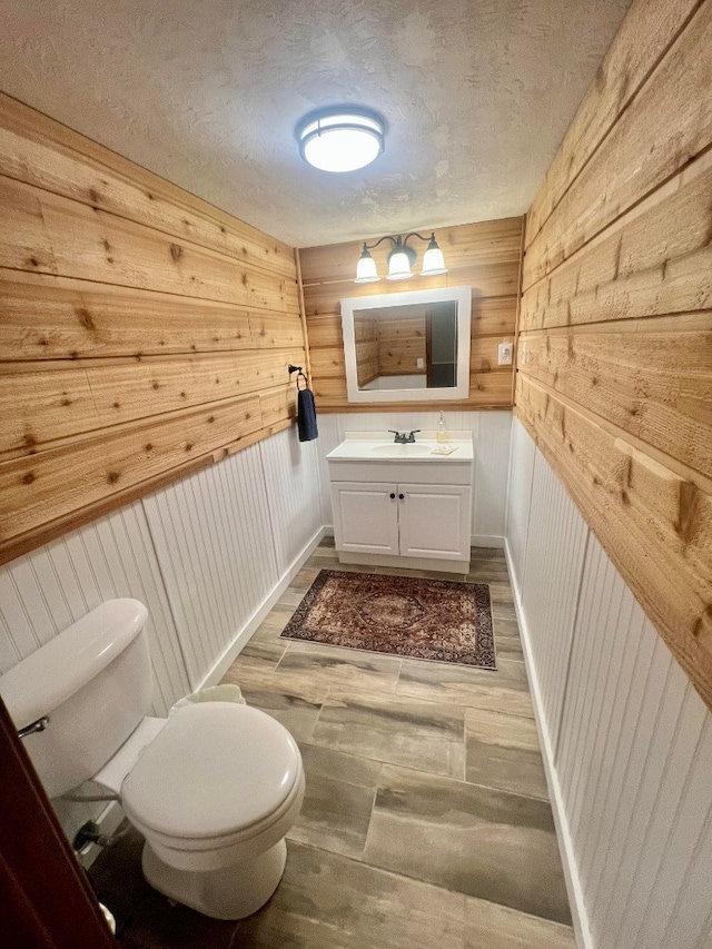 bathroom featuring vanity, wood finished floors, baseboards, a textured ceiling, and toilet