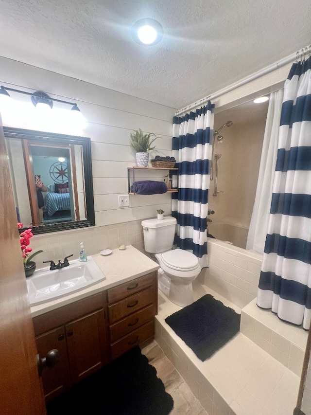 bathroom featuring shower / bath combination with curtain, toilet, a textured ceiling, and vanity