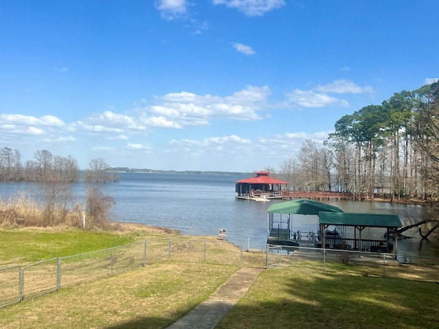 view of dock featuring fence, a lawn, a water view, and boat lift