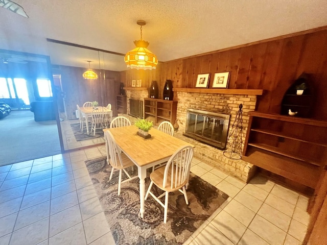 tiled dining area featuring a textured ceiling, a brick fireplace, and wood walls