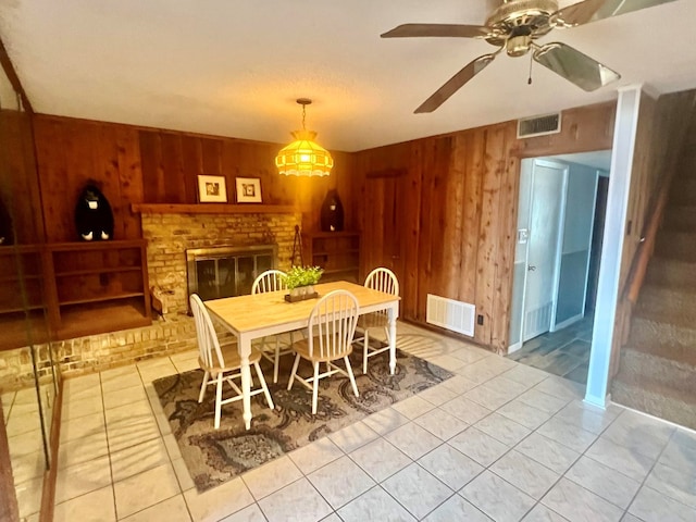dining area with visible vents, a ceiling fan, and wooden walls