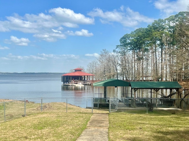 dock area with a water view, a lawn, and fence