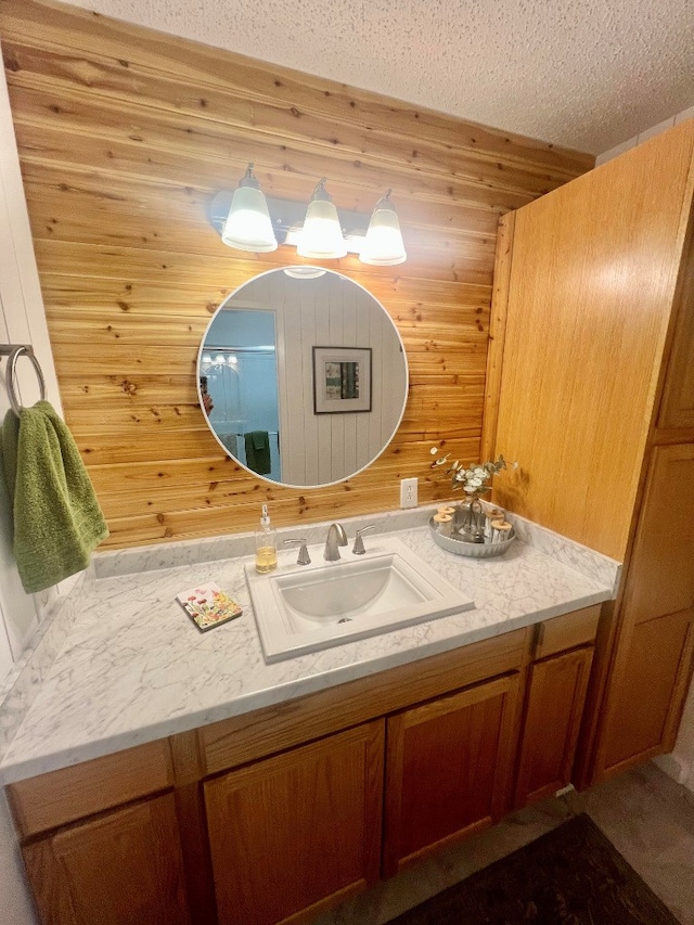 bathroom featuring vanity, wooden walls, and a textured ceiling
