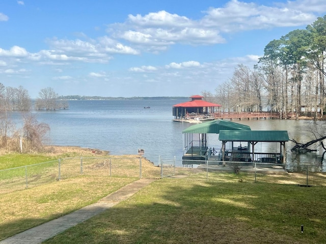 view of dock with a gazebo, a yard, fence, and a water view
