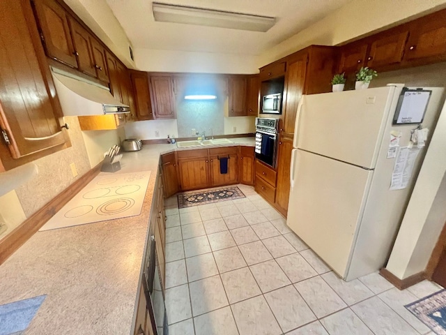 kitchen with white appliances, light tile patterned floors, a sink, light countertops, and exhaust hood