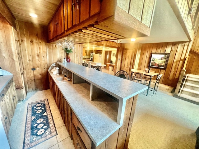 kitchen with a peninsula, brown cabinets, wood walls, and a sink