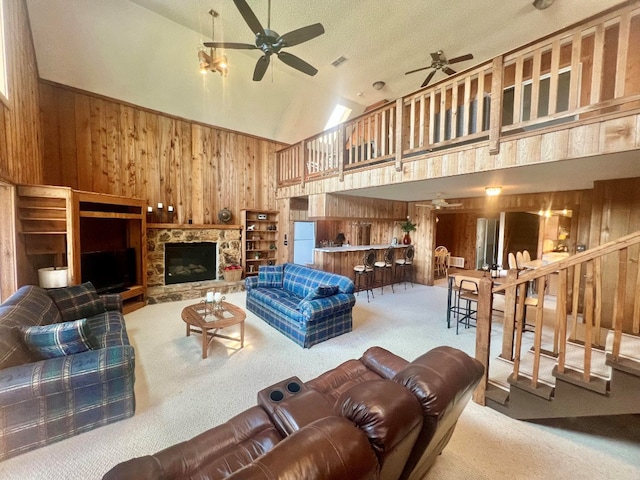 living room featuring wooden walls, high vaulted ceiling, ceiling fan, and carpet floors