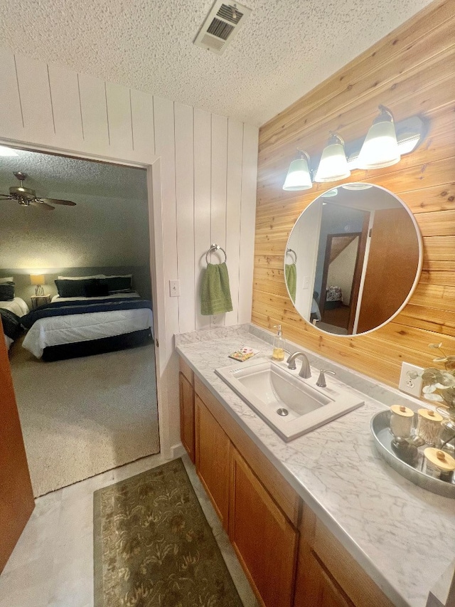 bathroom with visible vents, ensuite bathroom, a textured ceiling, wooden walls, and vanity