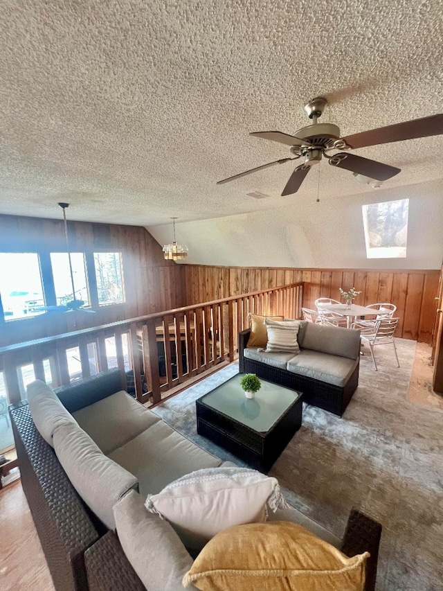 unfurnished living room with vaulted ceiling, wooden walls, ceiling fan with notable chandelier, and a textured ceiling