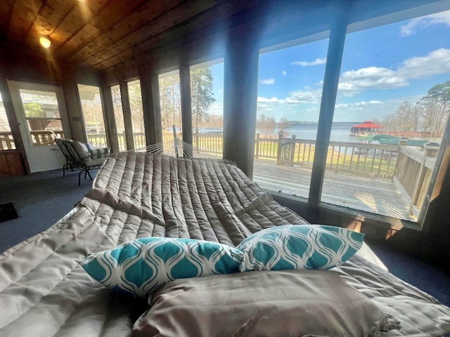 bedroom featuring access to exterior, wooden ceiling, and a water view