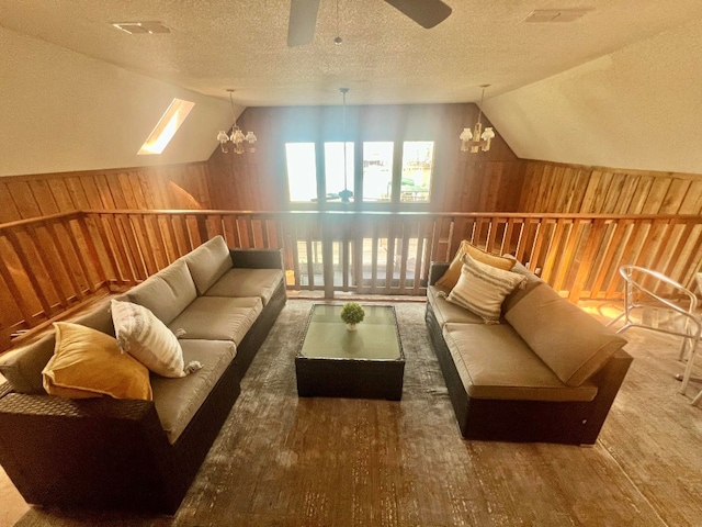 bonus room featuring wood finished floors, lofted ceiling, wood walls, a textured ceiling, and ceiling fan with notable chandelier