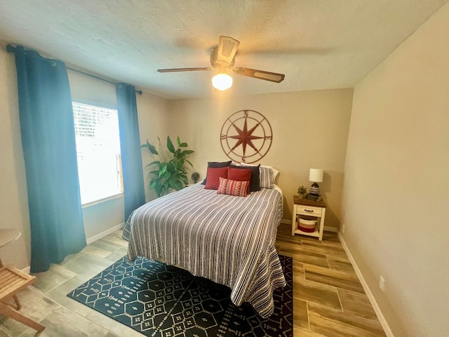 bedroom with a textured ceiling, wood finished floors, baseboards, and ceiling fan