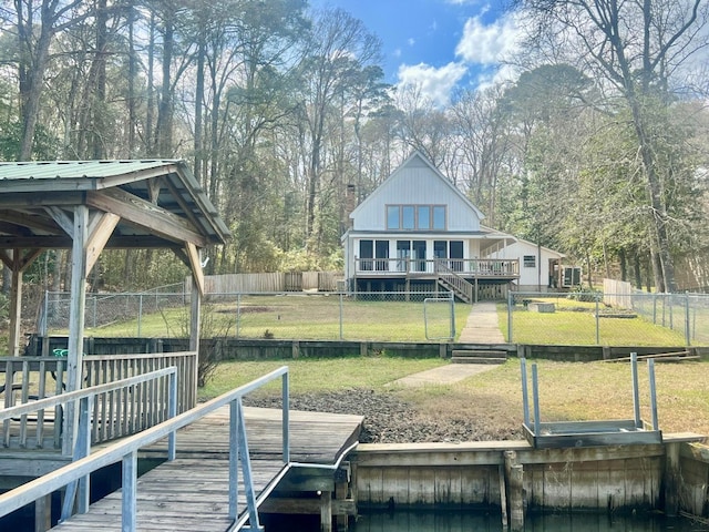 view of dock with a lawn, a wooden deck, and fence