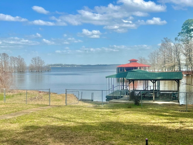 dock area with a gate, a yard, a water view, and fence